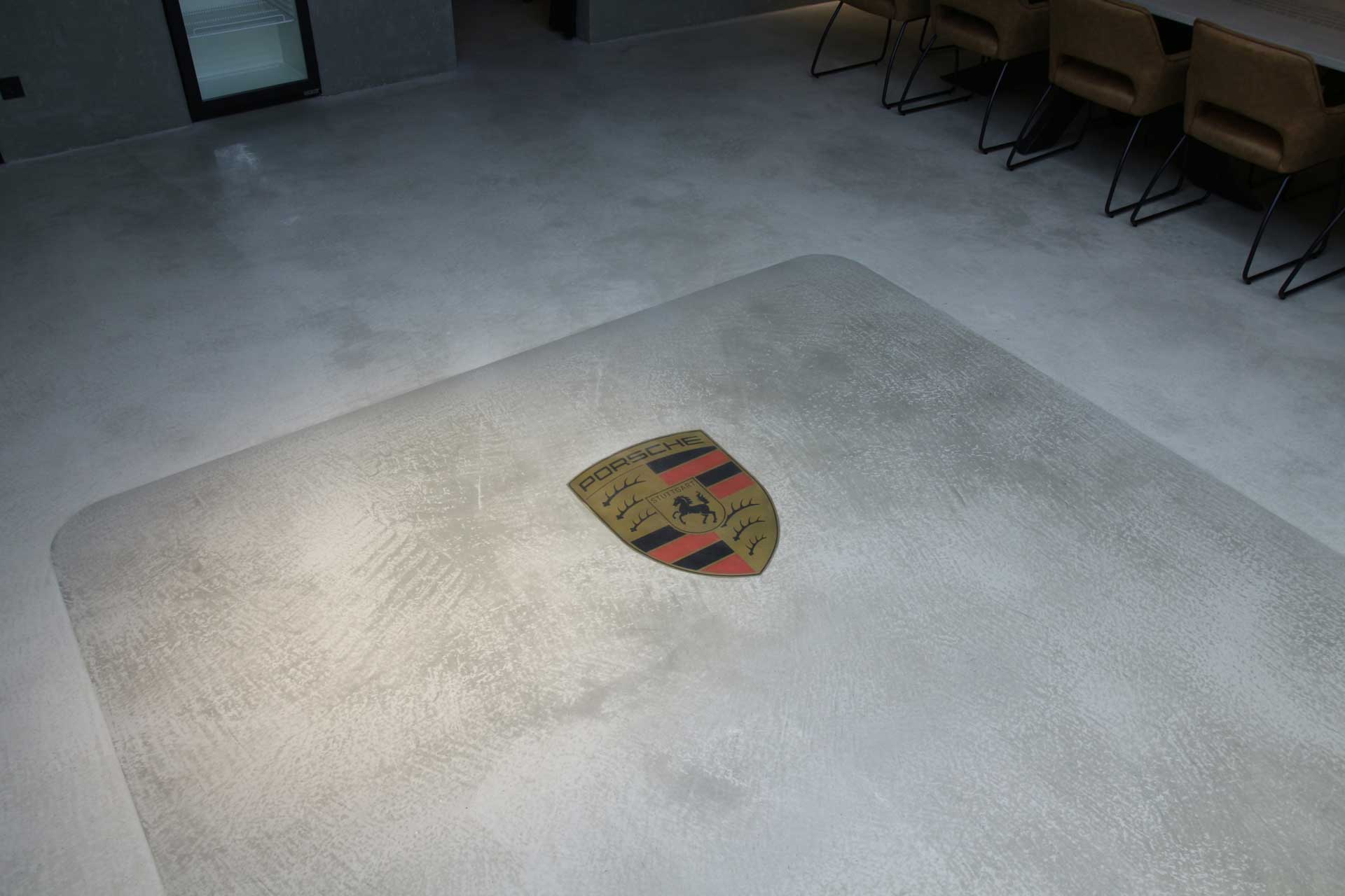gespachteltes Porsche Logo eingelassen in den gespachtelten Boden im Loft Design
